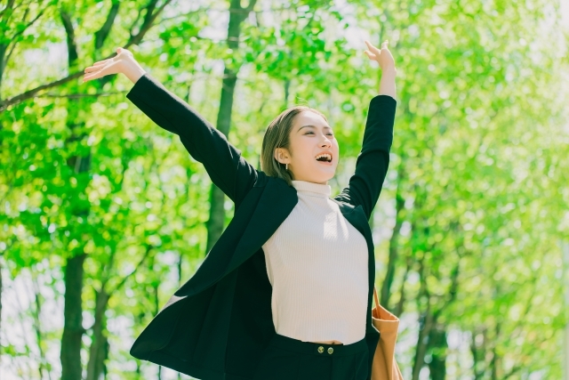 両手を広げて喜ぶスーツの女性の画像